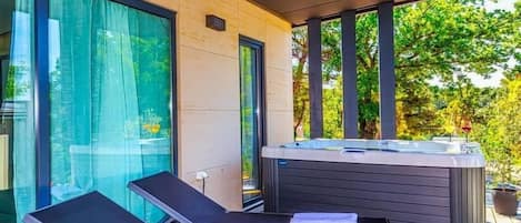 Un patio moderno al aire libre con dos sillones de descanso y un jacuzzi.