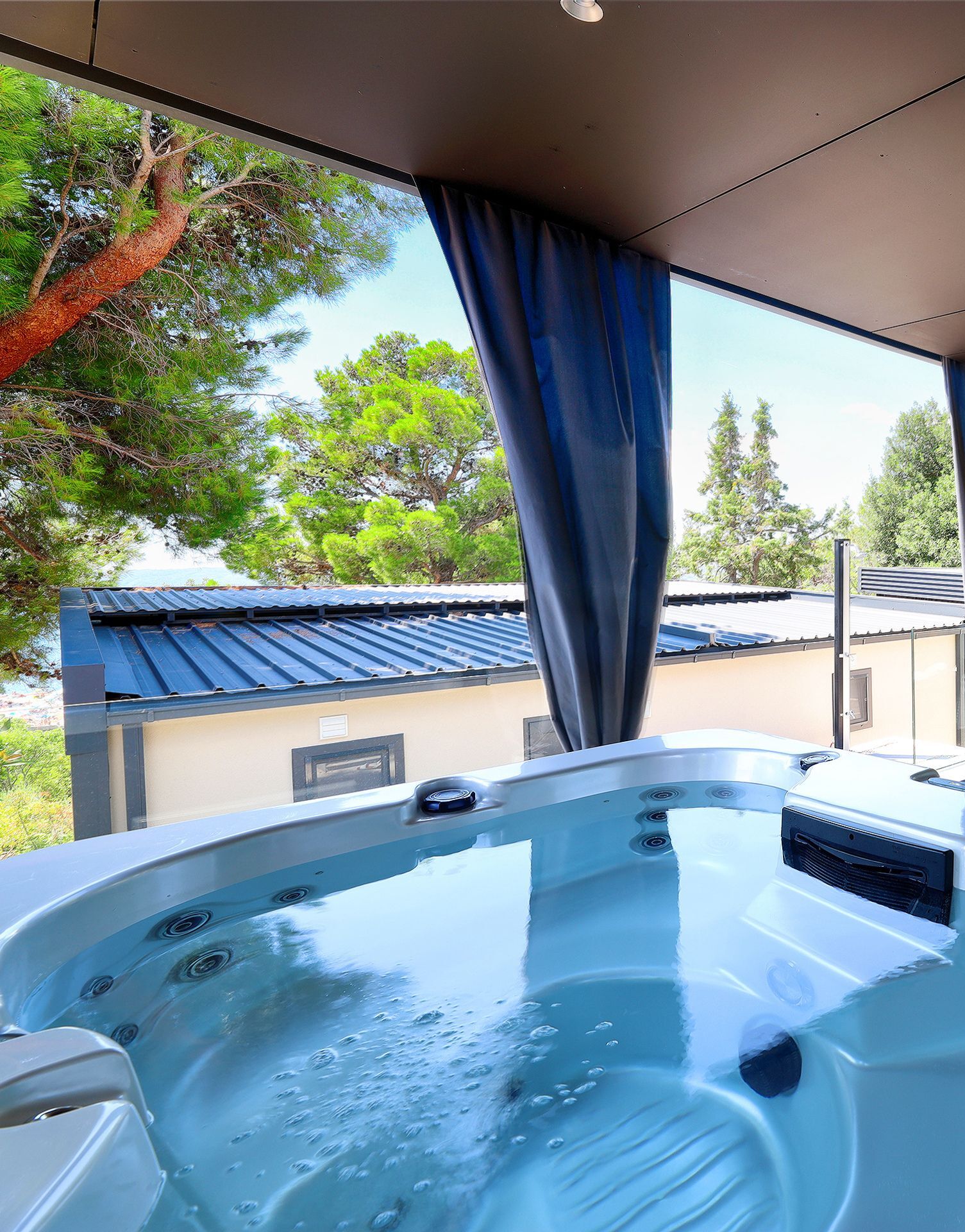 A hot tub with a view of trees and a building in the background.