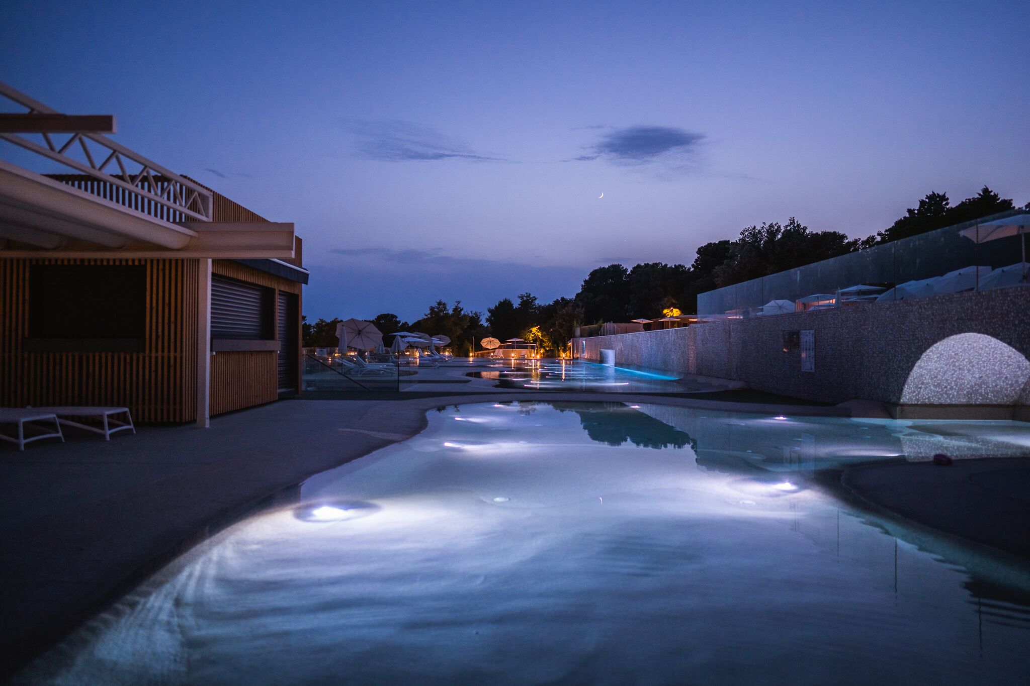 A swimming pool with a wooden deck and a covered area on the left.