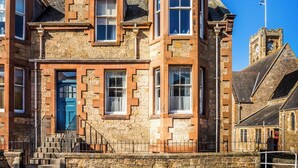 A historic stone building with a prominent tower, a blue door, and a staircase leading to the entrance. - Charming and comfortable apartment, centrally located with easy parking access. Sleeps 4 (North Berwick)