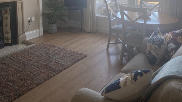 A living room with a fireplace, a dining area with a table and chairs, a sofa with cushions, and a view of the beach through large windows. - Stunning sea views, dog friendly holiday accommodation in North Berwick (North Berwick)