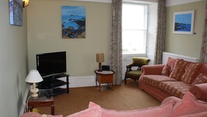 A living room with a television, a sofa, a chair, and a lamp. - Perfectly located for town and beach - Victorian terraced house near East Beach. Sleeps 7 (North Berwick)