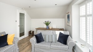 A room with a striped sofa set, a wooden bench, and a small table with a vase and a bowl. - Stylish first-floor apartment with private patio, just moments from the High Street. Sleeps 2 (North Berwick)