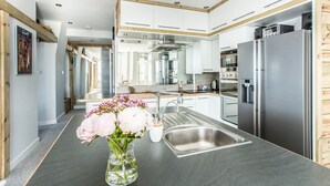 Una cucina moderna con elettrodomestici in acciaio inossidabile, un'isola centrale con un vaso di fiori e un soffitto in legno.