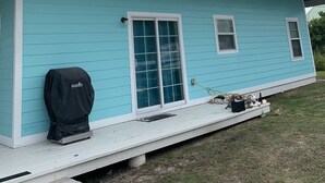 A two-story house with a light blue exterior, white trim, and a covered porch area. - Upstairs 3 BR, 2 bath home, 150 yds from beach with beautiful clear water. (Port Royale, South Bimini)