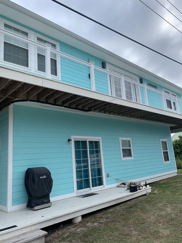 A two-story house with a light blue exterior, white trim, and a covered porch area. - Upstairs 3 BR, 2 bath home, 150 yds from beach with beautiful clear water. (Port Royale, South Bimini)