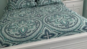 A bed with a patterned bedspread, a white headboard, and a nightstand with a lamp. - Upstairs 3 BR, 2 bath home, 150 yds from beach with beautiful clear water. (Port Royale, South Bimini)