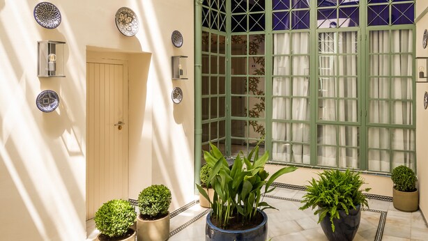 Un espace intérieur vaste, doté d’un plafond haut, d’une porte donnant sur une autre pièce et de plusieurs plantes en pot.