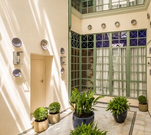 A spacious indoor area with a high ceiling, a door leading to another room, and several potted plants. - BYPILLOW Abril (Seville)