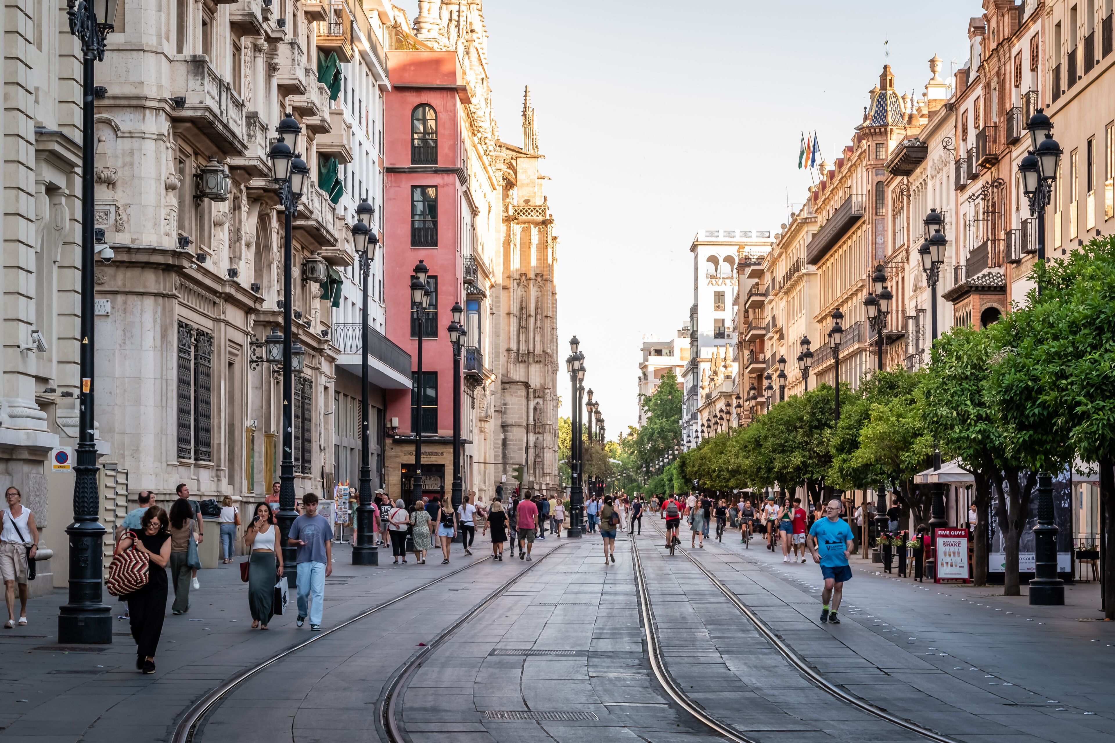 Une rue bordée de voies de tramway, de bâtiments historiques et d’une foule de piétons.