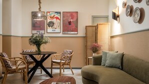 Un salon moderne avec une table ronde, des chaises en osier, un canapé et des œuvres d'art décoratives accrochées au mur.