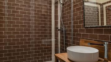 Une salle de bain avec des murs recouverts de carreaux marron, un meuble-lavabo en bois et un lavabo blanc.