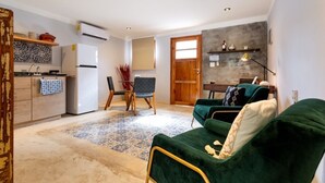 A compact living space with a kitchenette, a dining area, and a seating area with a green sofa. - Casa Dali, A+ location lovely house Paseo Montejo (Centro)