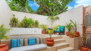 A sunlit outdoor seating area with a white bench, colorful cushions, and potted plants. - Casa Dali, A+ location lovely house Paseo Montejo (Centro)