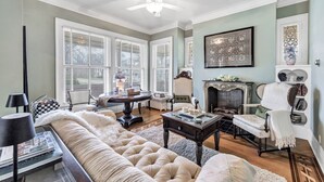 A living room with a sofa, armchairs, a fireplace, and a ceiling fan.