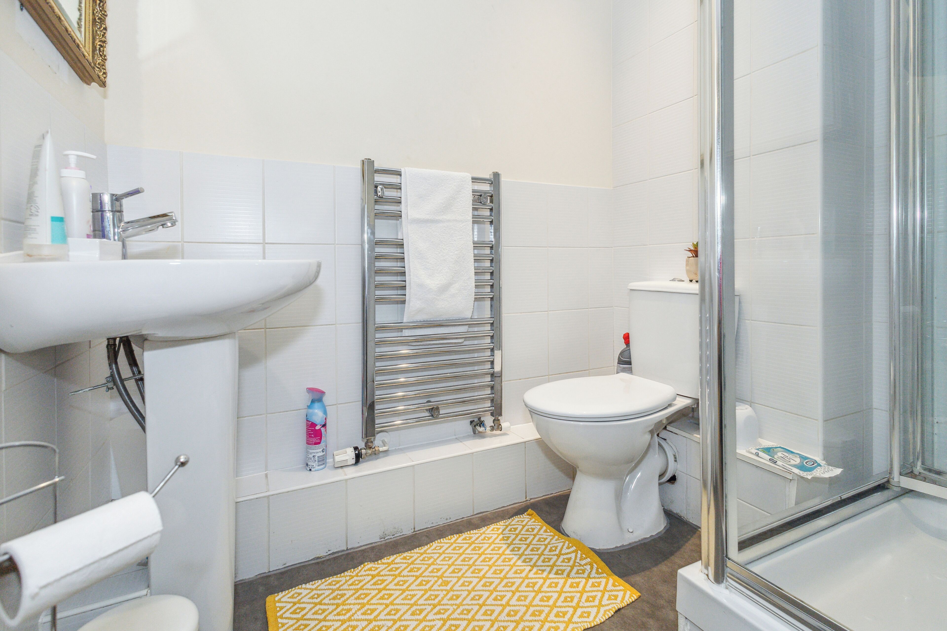 A bathroom with a sink, toilet, shower, and towel rack.