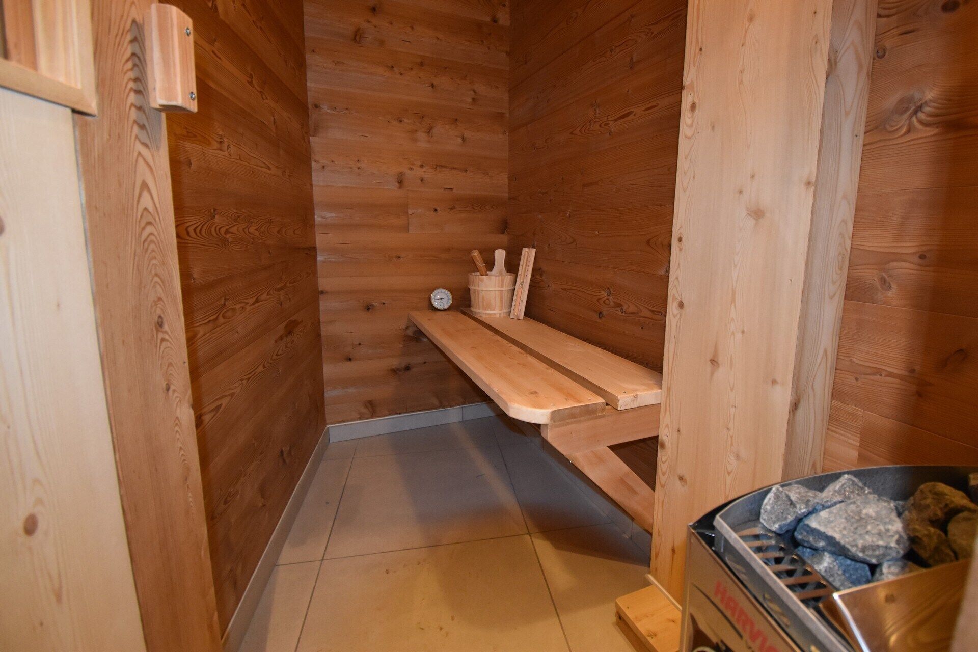 Un sauna en bois, avec un banc, un seau et un appareil de chauffage.