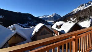 A wooden deck overlooking snow-covered cabins with a mountain view.