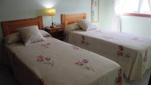 Two single beds with floral bedding, a bedside table with a lamp, and a window with curtains. - Apartment - Ground Floor - without terrace (Raxó)