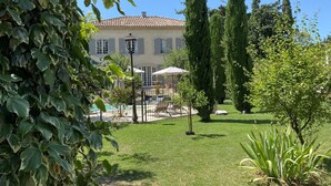 A well-maintained garden with a pool, a patio area, and a large building with a tiled roof. - Villa Agrippa (Orange)