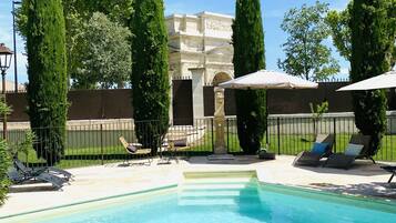Una piscina al aire libre de temporada, sombrillas, tumbonas