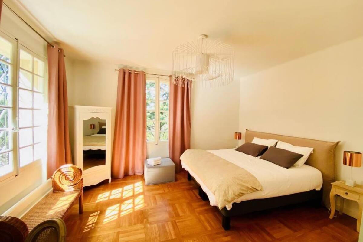 Un dormitorio con una cama grande, una silla, una mesita de noche y una ventana con cortinas.