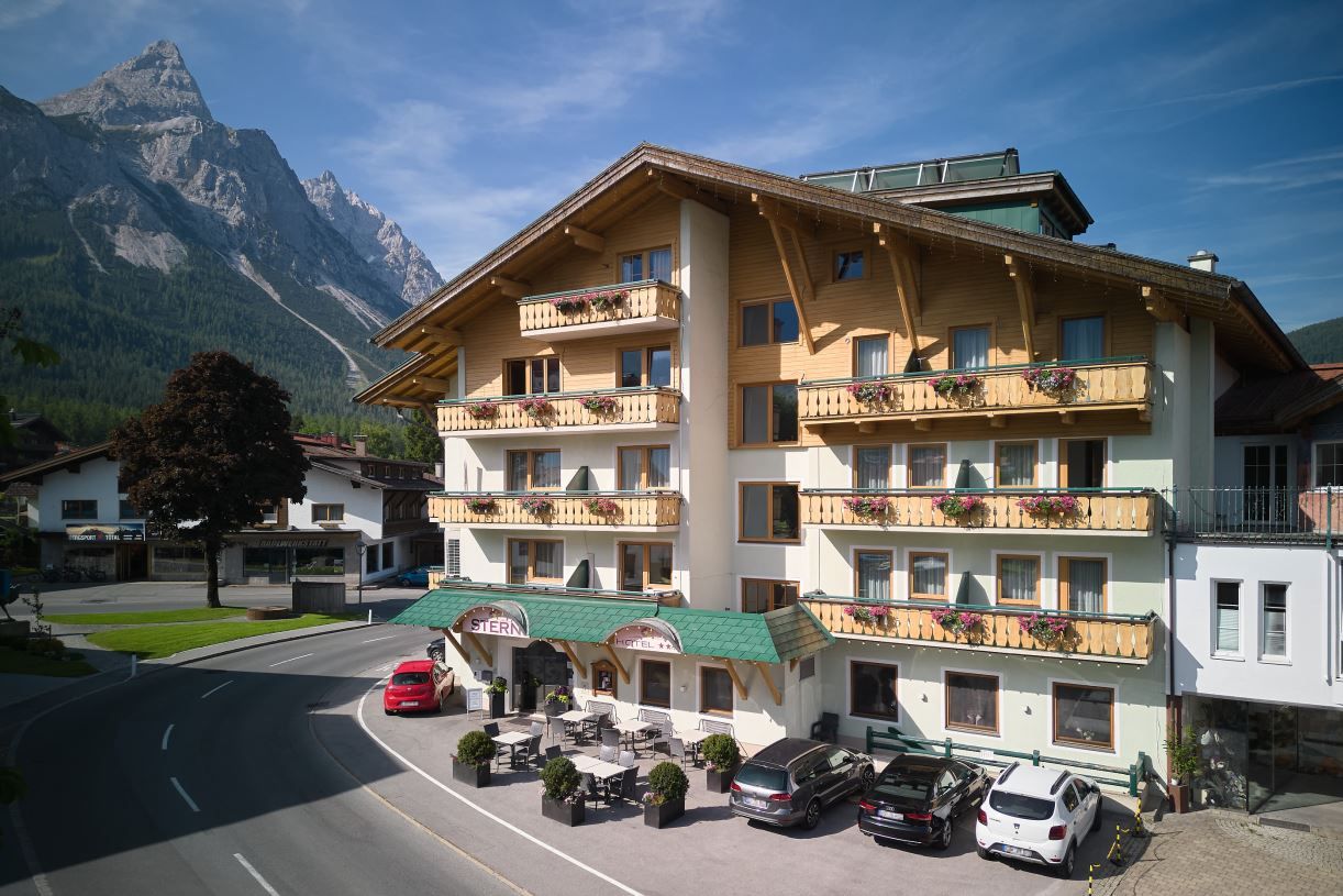 Un hôtel doté de nombreux balcons, d’un toit végétalisé et offrant une vue sur la montagne.