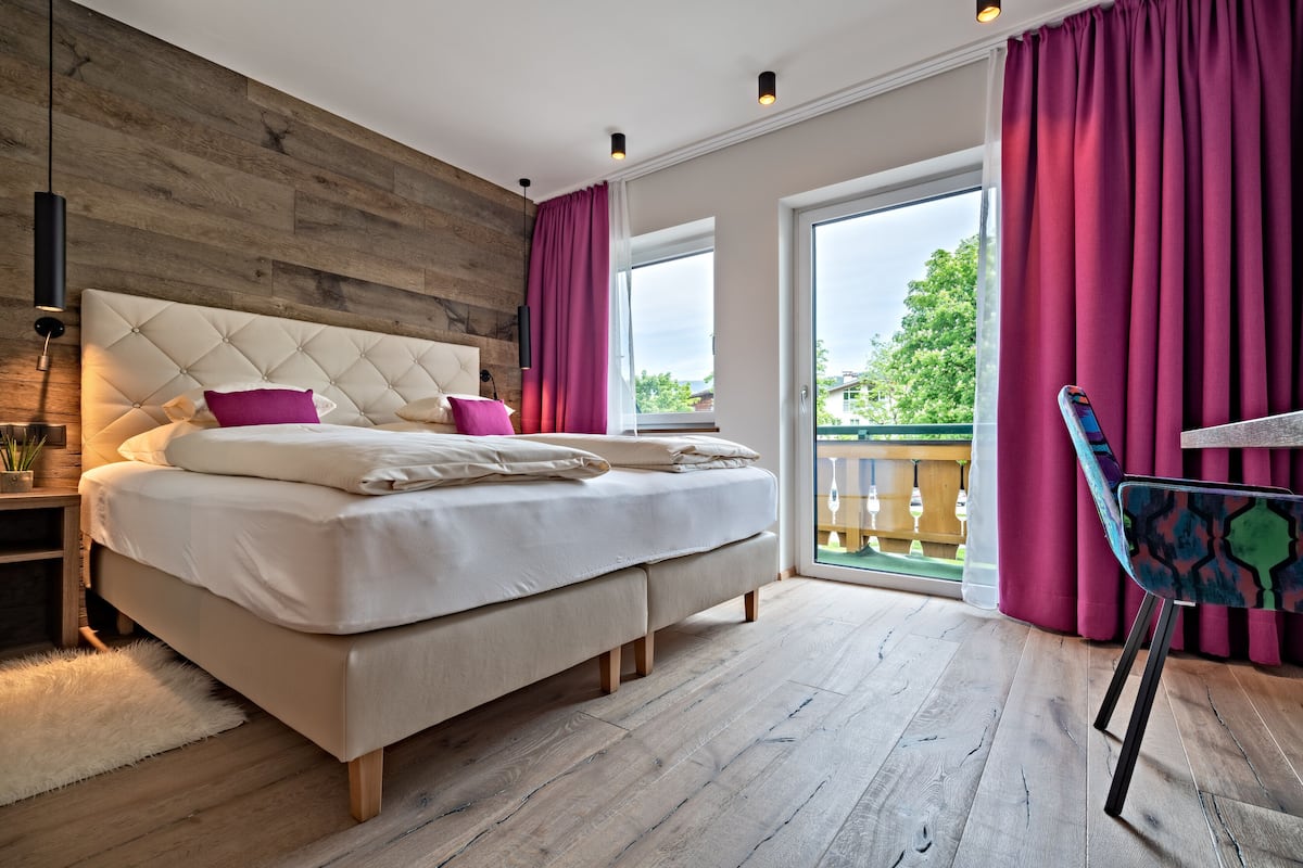 A bedroom with a large bed, wooden headboard, and a view of the outdoors through a sliding glass door.