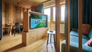 A wooden interior with a TV, a dining area, and a sofa. - Hotel Stern (Ehrwald)
