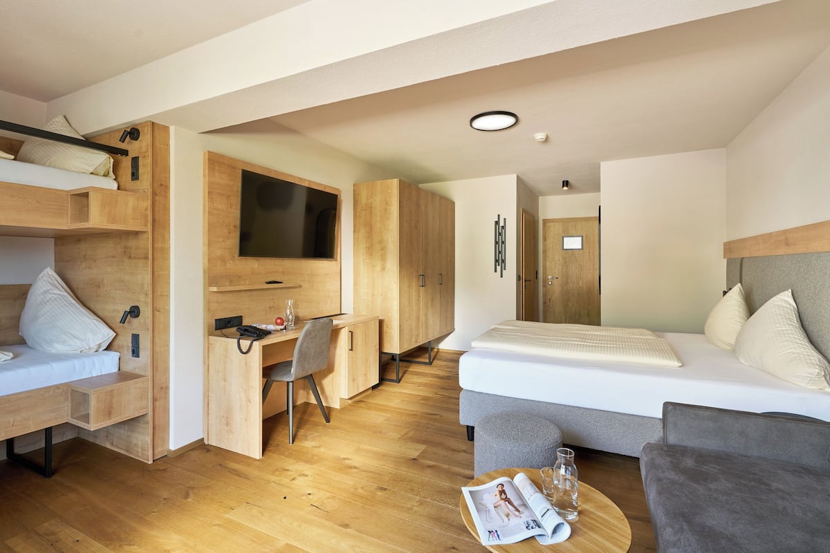 A modern, compact room with a bed, a desk, and a seating area.