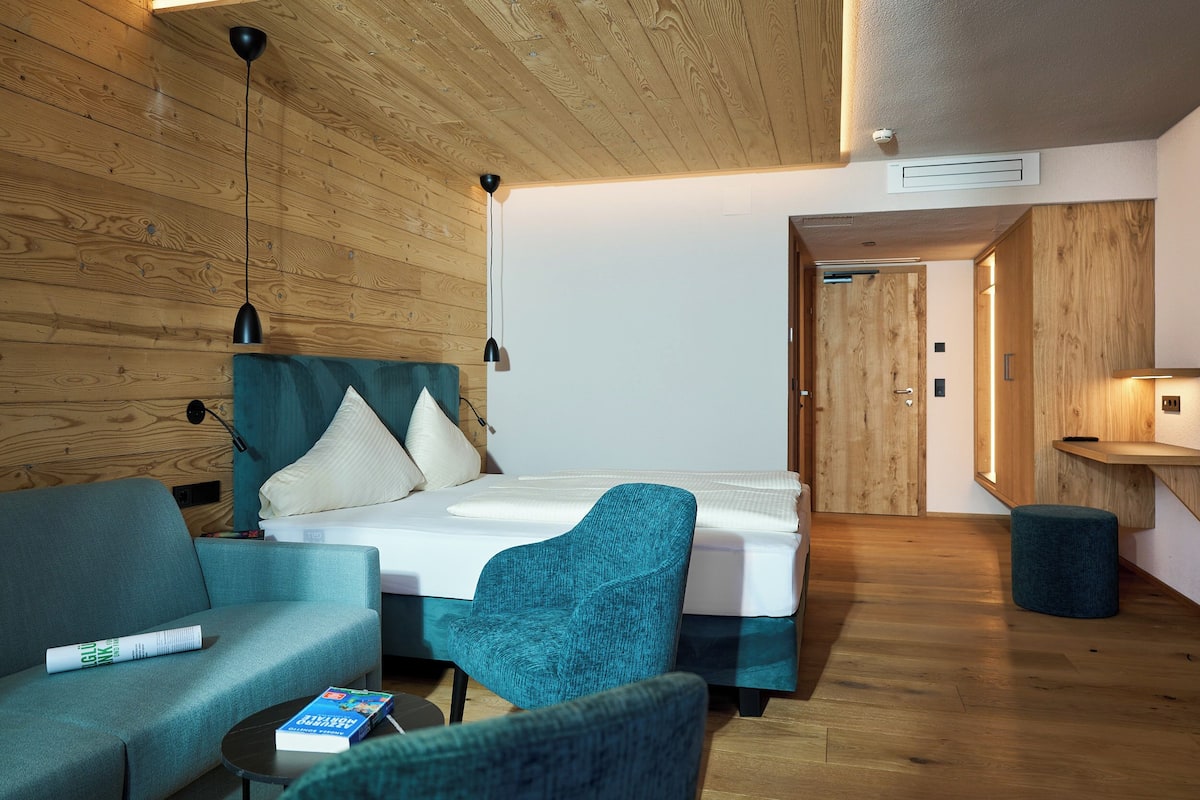 A modern room with a bed, a sofa, a chair, and a small table.