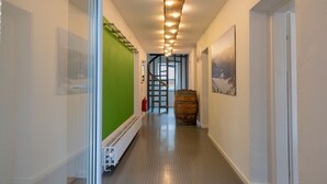 Een hal met een groene wand, een houten vat en een wenteltrap op de achtergrond.