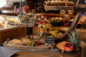 A buffet with a variety of cheeses, fruits, and a sign indicating 'Bergkäse Variations'. - Hotel Restaurant tauernhex (Piesendorf)