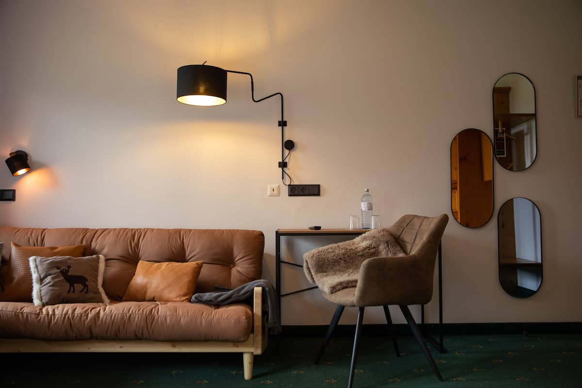 Ett rum med en brun lädersoffa, en fåtölj, ett litet bord och två speglar som hänger på väggen.