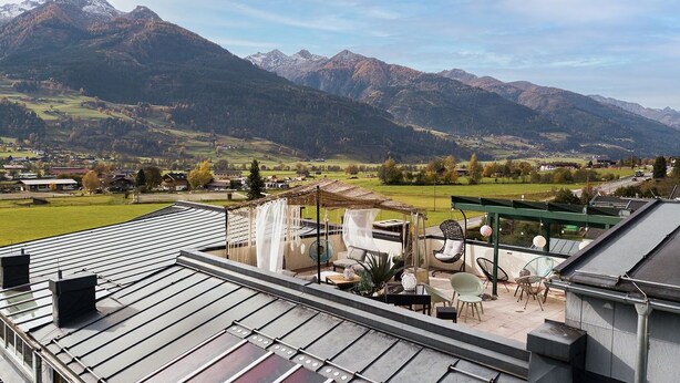 Terraza en la azotea con vistas a montañas, mobiliario exterior y una pérgola.