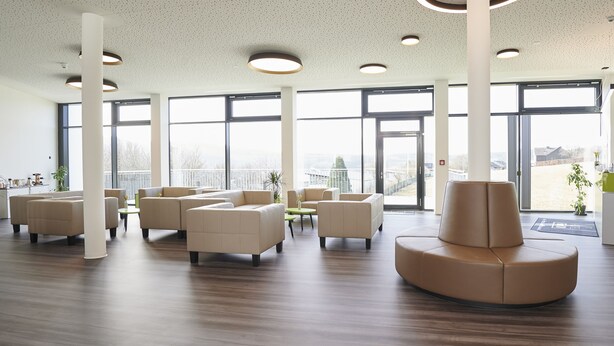 Un vestíbulo espacioso con techos altos, ventanas grandes y una zona de estar moderna.