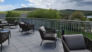 Un balcón con mobiliario de mimbre y vistas a un paisaje verde.