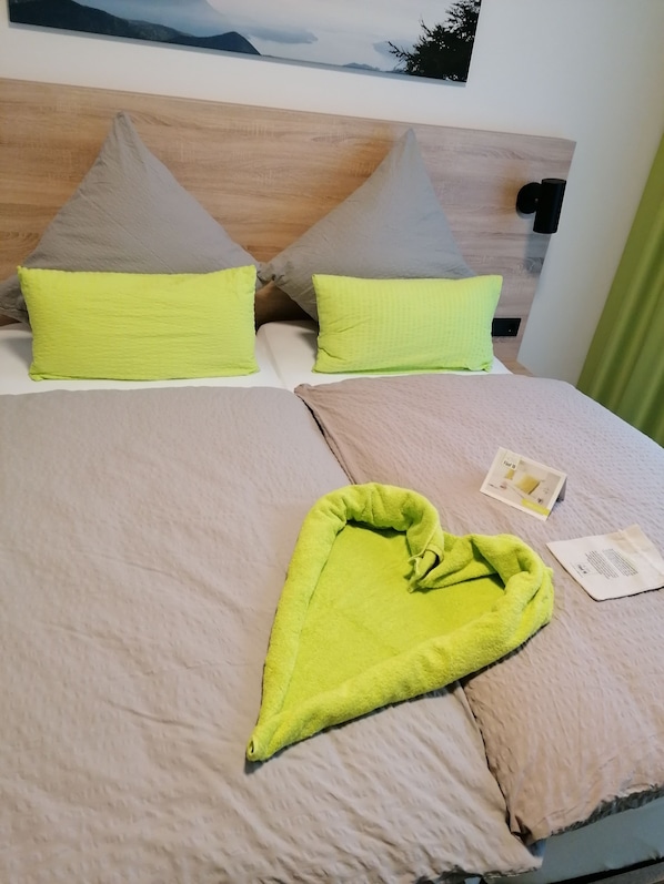 A neatly made bed with two pillows, a blanket, and a folded towel. - Hotel Fünf10 (Netphen)