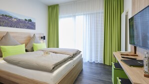 Una habitación de hotel con cama, escritorio, televisor y un cuadro en la pared.