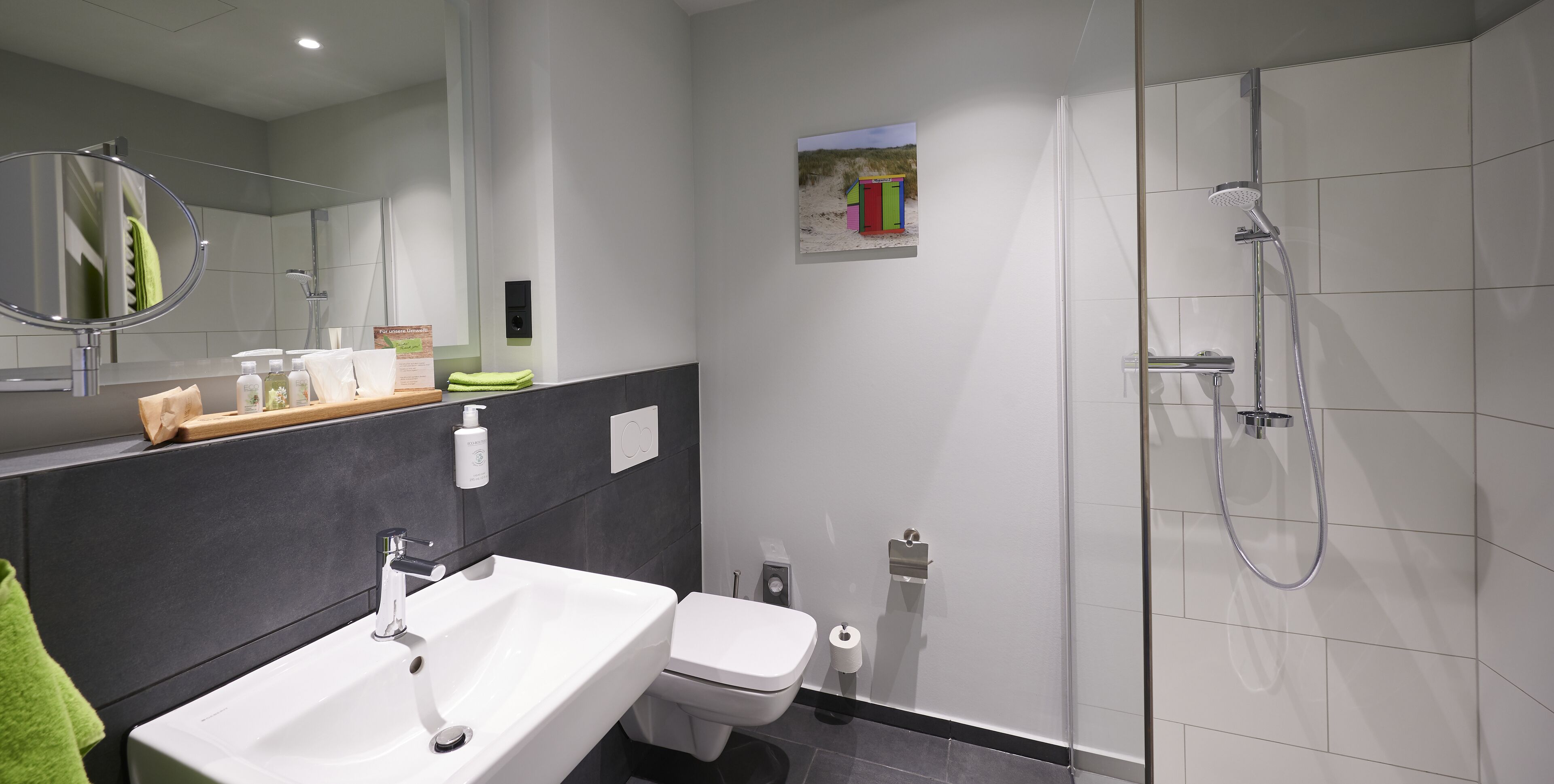 A modern bathroom with a white sink, toilet, and shower.