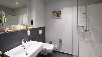 A modern bathroom with a white sink, toilet, and shower.
