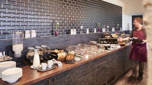 Un bufé de desayuno con diferentes alimentos y una persona atendiendo.