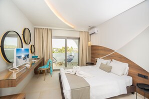 Una habitació d'hotel moderna amb un llit gran, una televisió, un escriptori amb cadira i un balcó amb vistes.