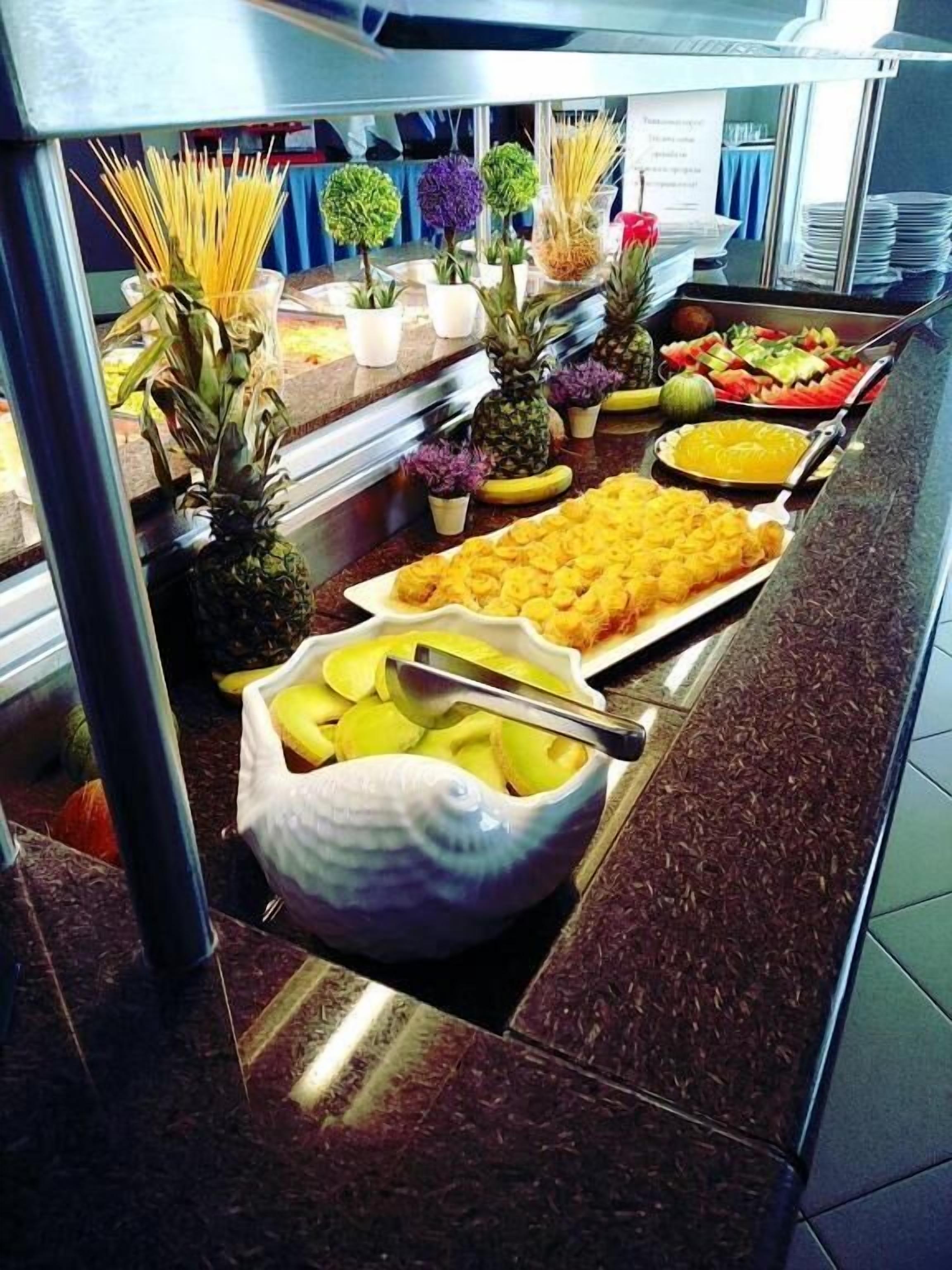 Ein Buffet mit verschiedenen Speisen, darunter Obst, Gemüse und Pasta.