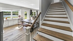 Eine moderne Küche mit Seeblick, ein Essbereich mit einer Bank und eine Holztreppe.