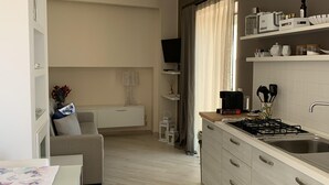 Une cuisine moderne avec un coin repas, des meubles blancs et un téléviseur à écran plat.