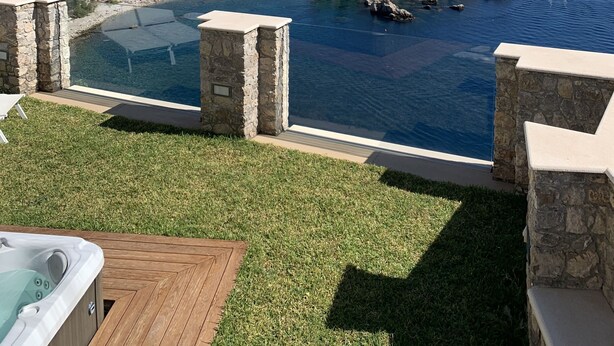 Une vue sur la piscine, avec un jacuzzi, un ciel bleu azur et un paysage magnifique sur la mer et les îles rocheuses.