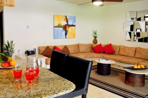 Un salon moderne avec un canapé marron, des coussins rouges, une table basse et un tableau accroché au mur.