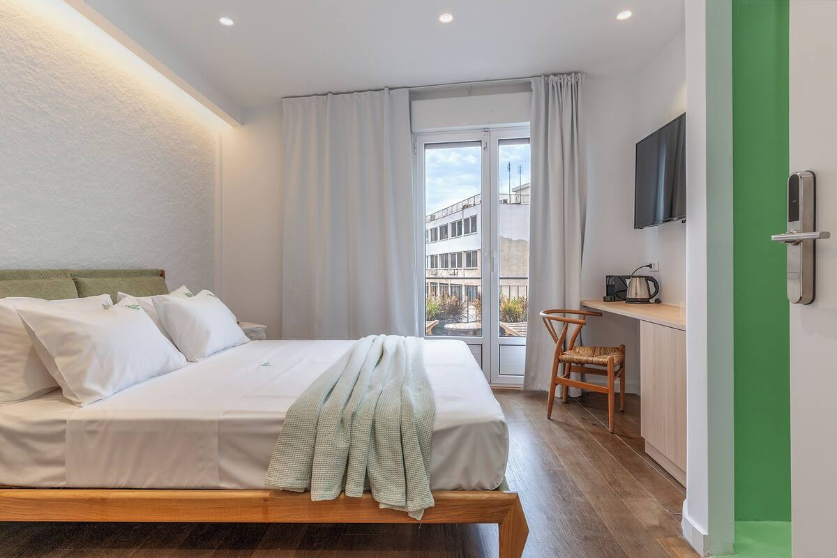 A bedroom with a bed, a desk, a chair, and a TV.