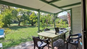 A covered patio with a table and chairs, a laptop, and a blue chair.